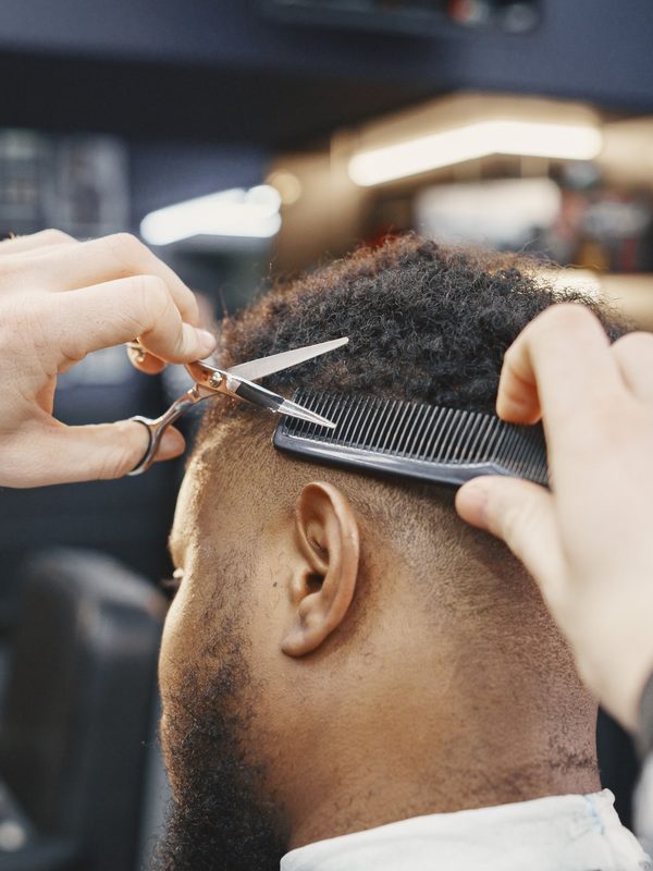 Barber cutting hair with scissors and comb
